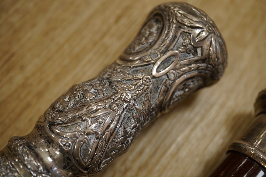 Three 19th century walking sticks, two with silver tops to include a dogs head example, one with unmarked embossed white metal top, largest 97cm in length